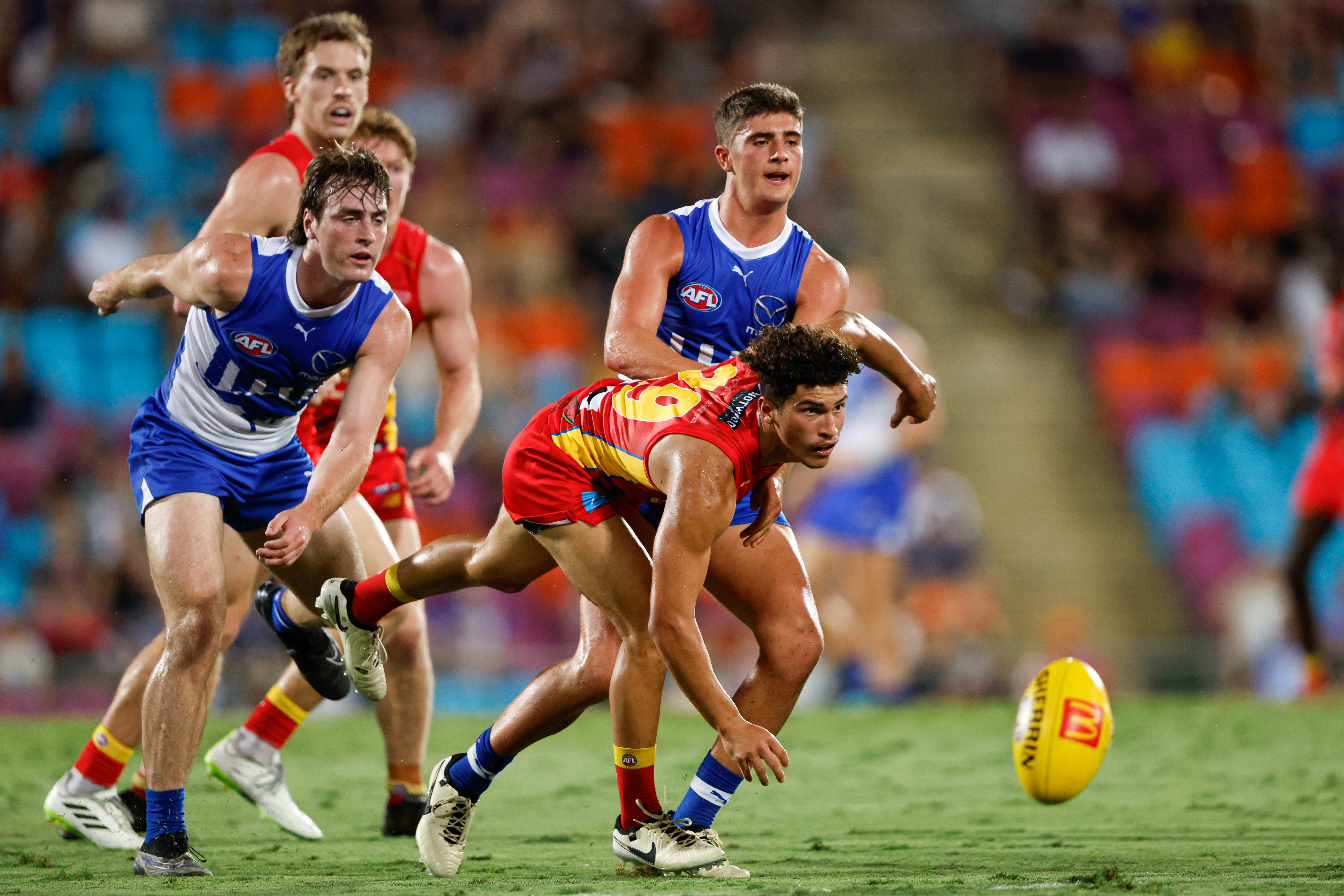 gold coast suns player diving down to grab AFL ball 